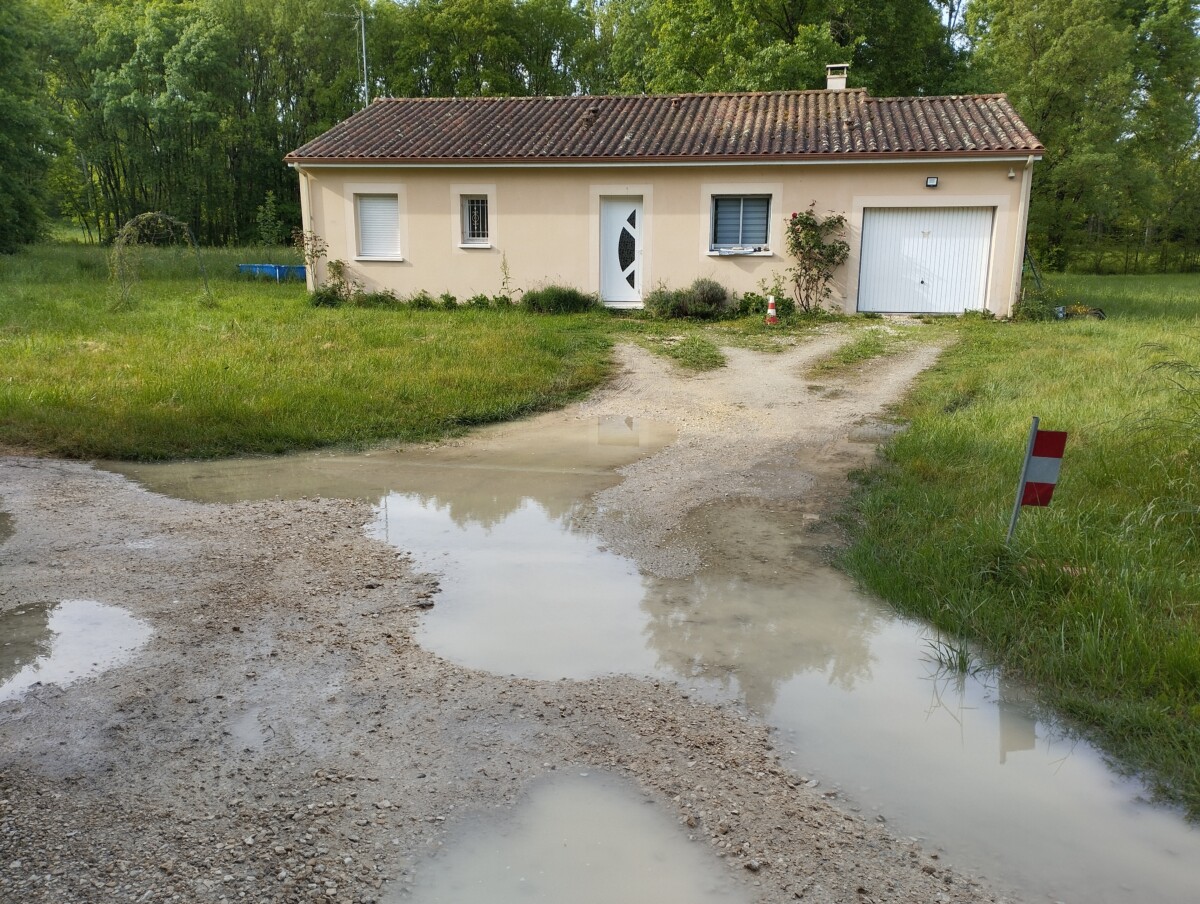 Vue d'un accès de maison individuelle non stabilisée avec de grosses flaques d' eau... Vue avant travaux.