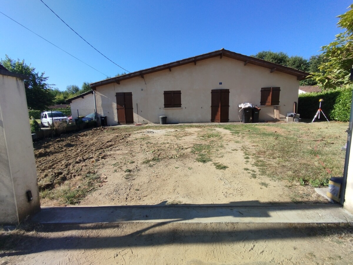 Vue la cour cour en terre battue d'une maison individuelle. Avant travaux.