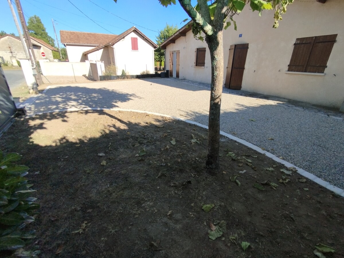 Vue de la cour après travaux. Cours en gravillons et bordure pavée.