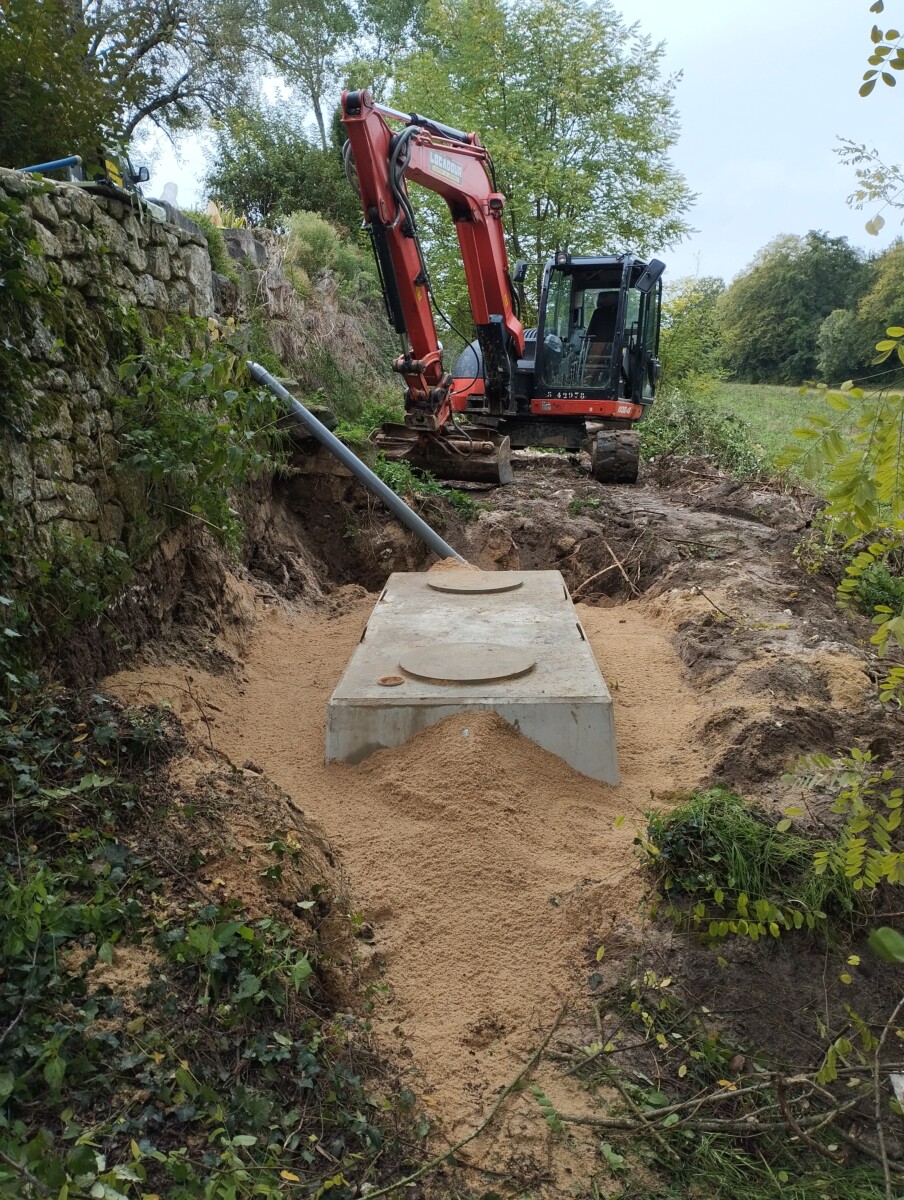 Vue d'une pelle mécanique pour le remplacement d'une fosse plastique par une fosse béton.