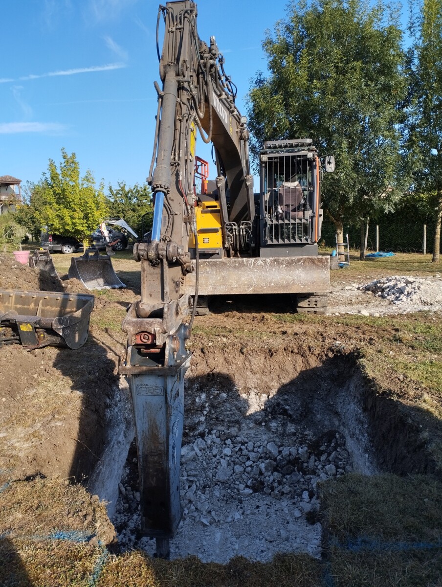 Utilisation d'une pelle mécanique équipée d'un brise roche afin d'atteindre la profondeur adéquate pour poser filière compacte agrée 5EH avec pompe de relevage.